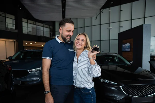 Feliz Casal Caucasiano Abraço Mulher Segurando Novas Chaves Carro Showroom — Fotografia de Stock