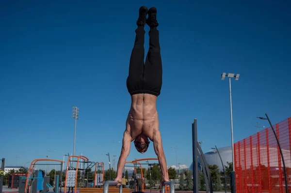 Shirless Άνθρωπος Κάνει Handstand Παράλληλα Μπαρ Στο Γήπεδο Του Αθλητισμού — Φωτογραφία Αρχείου