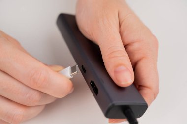 Bir kadın siyah bir limana beyaz tip C kablosu yerleştiriyor.