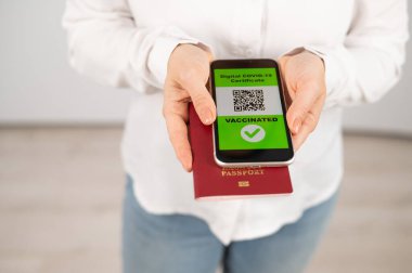 Pasaportu ve telefonu olan bir kadın aşı ile ilgili QR kodu taşıyor.