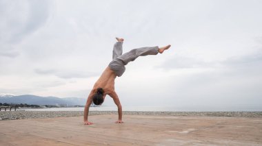 Çakıl taşlı plajda ters takla atan beyaz bir adam.