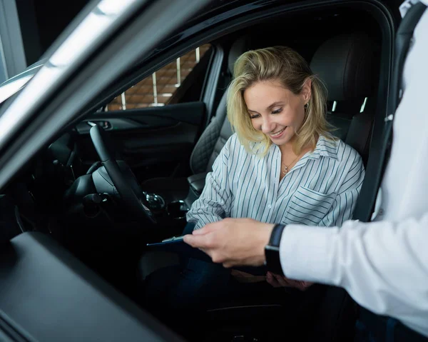 Happy caucasian woman signing a contract to buy a car