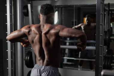 Yakışıklı afro-amerikalı adam spor salonunda sırt kaslarını gösteriyor.
