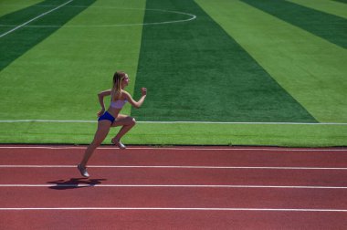 Genç beyaz kadın açık hava stadyumunda koşuya çıktı.