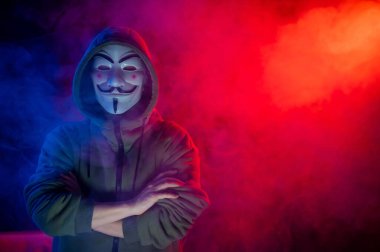 5 Haziran 2022 Novosibirsk, Rusya: Kırmızı-mavi dumanda Anonymous 'un kapüşonlu portresi