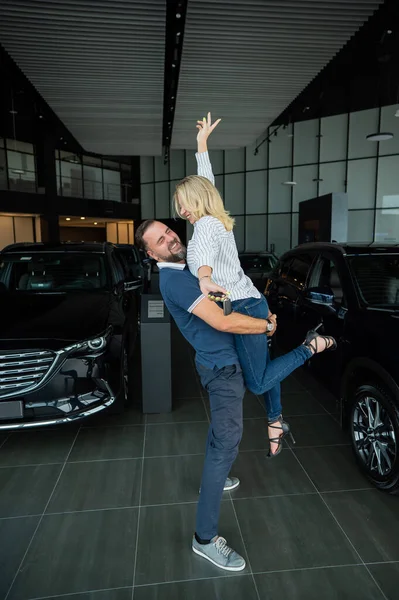 Feliz Casal Caucasiano Abraçando Enquanto Compra Carro Novo Uma Concessionária — Fotografia de Stock