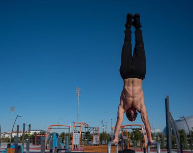 Spor sahasındaki paralel parmaklıklarda amuda kalkıyor.