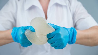 Bir plastik cerrah silikon göğüs implantlarının gücünü onları sıkarak gösterir.
