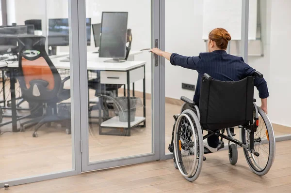 Rudowłosy Biały Kobieta Wózku Inwalidzkim Próbuje Otworzyć Drzwi Biurze — Zdjęcie stockowe