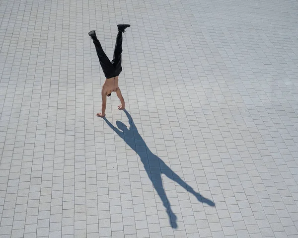 Tişörtsüz bir adam dışarıda elini kolunu sallayarak yürüyor. Yukarıdan görüntüle