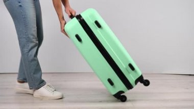 Kadın valizini yere koyar ve yukarıdan atlar. Kız bavulu test ediyor.