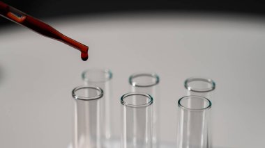 Laboratuvar asistanının, pipetten kan damlatarak test tüpüne kan damlattığı yakın plan.