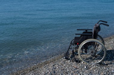 Kayalık bir sahilde boş bir tekerlekli sandalye.