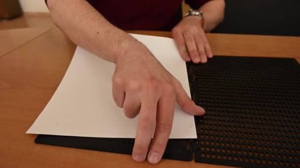 Seorang Pria Buta Menempatkan Selembar Kertas Dalam Stensil Braille Khusus — Stok Video