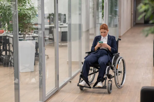 Biała Kobieta Korzystająca Telefonu Komórkowego Wózku Inwalidzkim Biurze — Zdjęcie stockowe