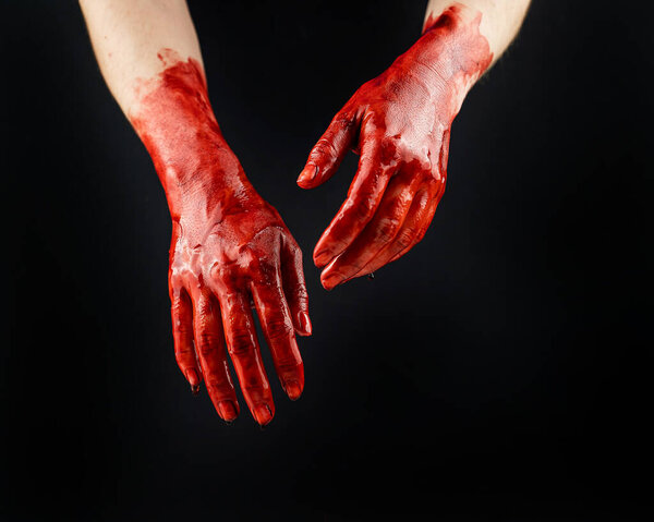 Womens hands in blood on a black background