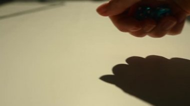 Bir kadın beyaz bir masaya mavi küpleri fırlatıyor. Yavaş çekim