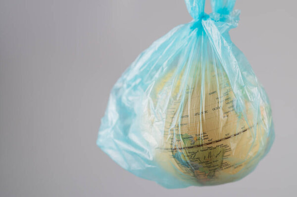A woman is holding a globe in a plastic bag on a white background