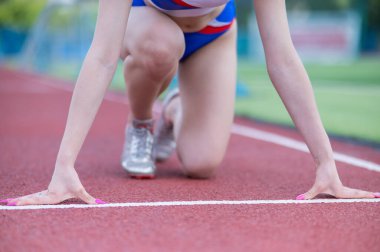 Kadın bacaklarına yakın çekim. Stadyumdaki koşucu yarış için hazır.