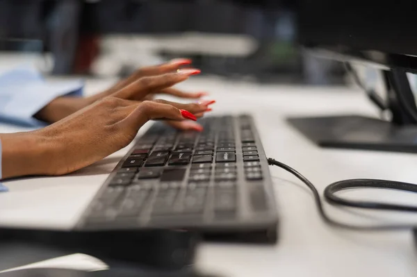 African woman is typing on the keyboard. Close-up of female hands of an office worker
