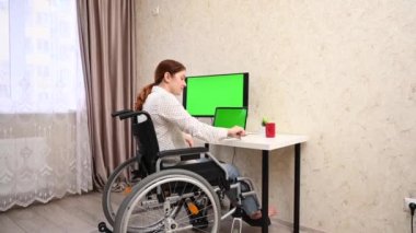 Caucasian woman with disabilities working at the computer while sitting in a wheelchair
