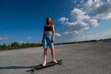 Beyaz bir kadın uzun bir sörf tahtasına biniyor.