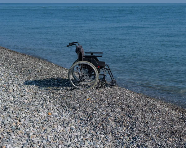 Una Sedia Rotelle Vuota Una Spiaggia Rocciosa — Foto Stock