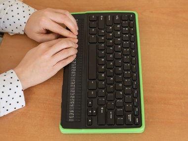 Kör bir kadın Braille ekranı ve klavyesi olan bir bilgisayar kullanıyor. Özel aygıt