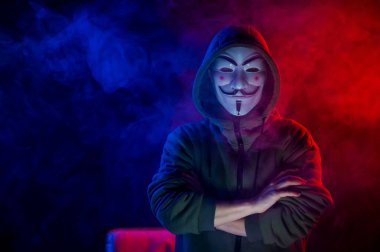 5 Haziran 2022 Novosibirsk, Rusya: Kırmızı-mavi dumanda Anonymous 'un kapüşonlu portresi