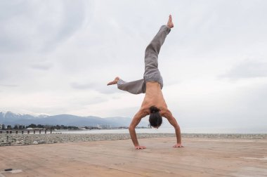 Çakıl taşlı plajda ters takla atan beyaz bir adam.