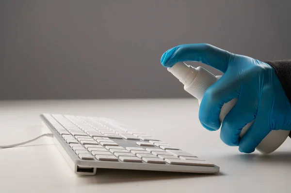 Close-up of a woman disinfects a white computer keyboard. Slow motion