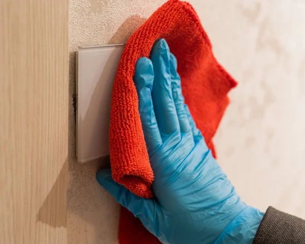 Caucasian woman in gloves wipes touch switch with napkin