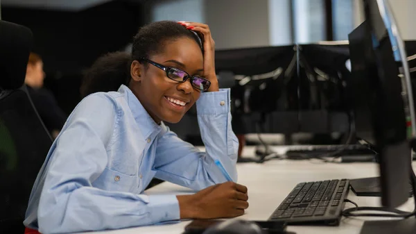 African young woman typing on a computer at her desk in the office