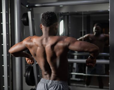 Yakışıklı afro-amerikalı adam spor salonunda sırt kaslarını gösteriyor.