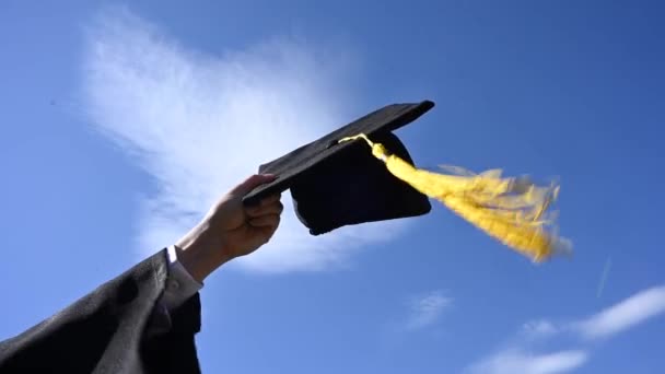 Close Van Een Vrouwenhand Met Een Graduatiekap Tegen Blauwe Lucht — Stockvideo