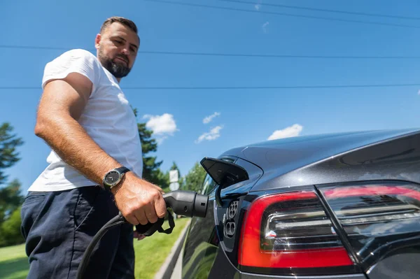 Kaukaski Mężczyzna Podłączyć Ładowarkę Samochodu Elektrycznego — Zdjęcie stockowe