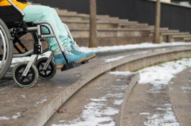 Kışın parkta merdivenlerin yanında tekerlekli sandalyedeki kadın.