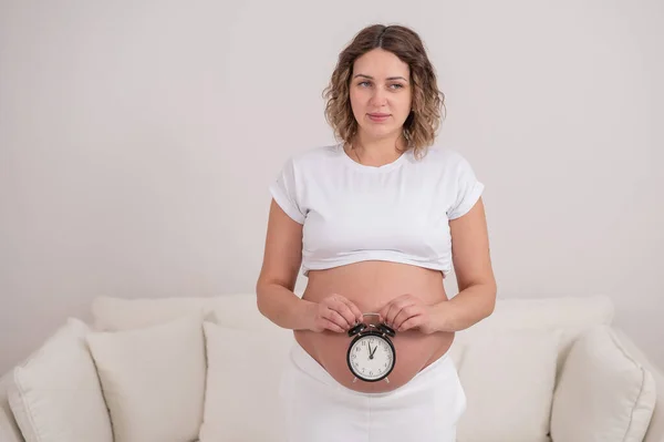 Μια Έγκυος Γυναίκα Γυμνή Κοιλιά Κρατάει Ξυπνητήρι Προβλεπόμενη Ημερομηνία Γέννησης — Φωτογραφία Αρχείου