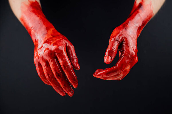 Womens hands in blood on a black background