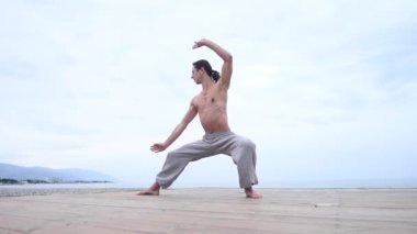 Kafkasyalı, uzun saçlı, dışarıda qigong antrenmanı yapan bir adam.