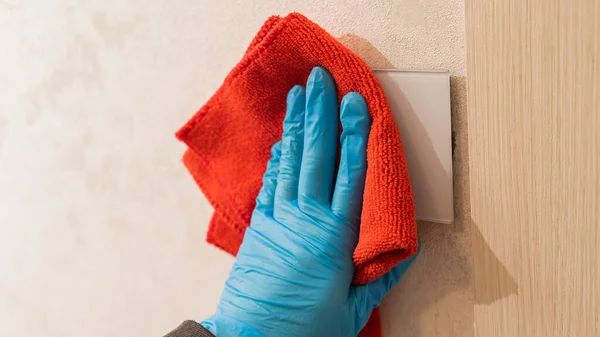 Caucasian woman in gloves wipes touch switch with napkin