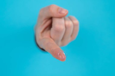 Bir kadın elini mavi bir kağıttan uzatır ve kontakt lens tutar.