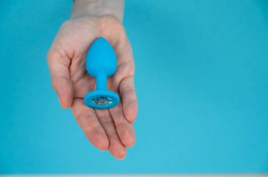 Mavi arka planda mavi anal tıpa tutan bir kadın.