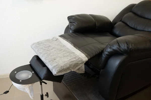Black pedicure chair with dust vacuum cleaner in beauty salon