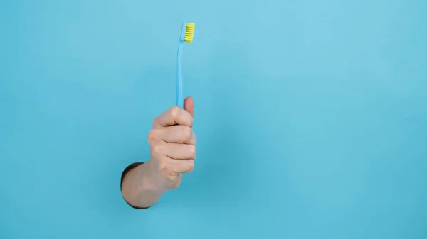 Womans Hand Sticks Out Blue Paper Background Holds Toothbrush — Stock Photo, Image