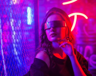 Güneş gözlüklü beyaz kadın. Sis içinde Neon Stüdyoda poz veriyor.