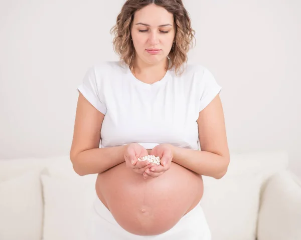 Een Zwangere Vrouw Houdt Een Handvol Witte Pillen Vast — Stockfoto