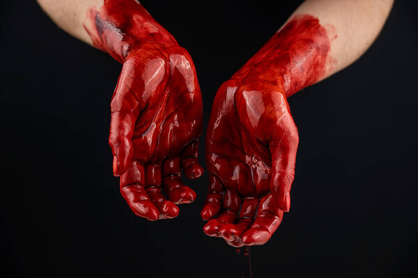 Womens hands in blood on a black background