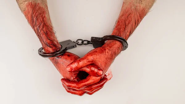 白いテーブルの上に折り畳まれた手錠で血を流した男の手 — ストック写真