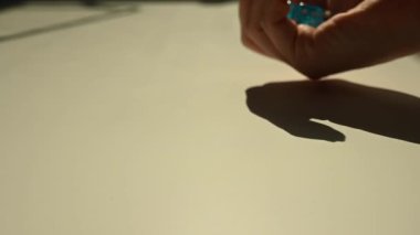 Bir kadın beyaz bir masaya mavi zar atıyor. Yavaş çekim